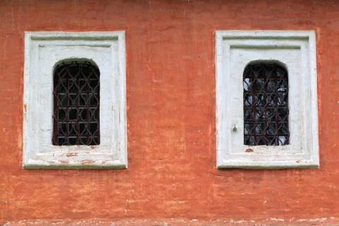 Two windows with bars on the red wall Stock Photos