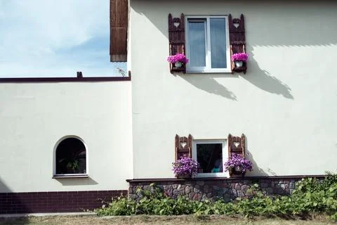 Two windows with flower pots on the facade of the building Stock Photos