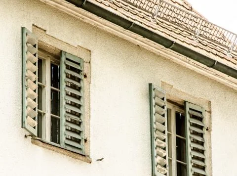 Two windows with green window shutters and old roof... Stock Photos