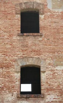 Two Windows of an old brick building with iron grilles Stock-Fotos