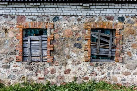 Two windows in an old building boarded up by boards Stock Photos