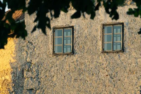 Two windows on an old building sidelit by setting sun Stock Photos