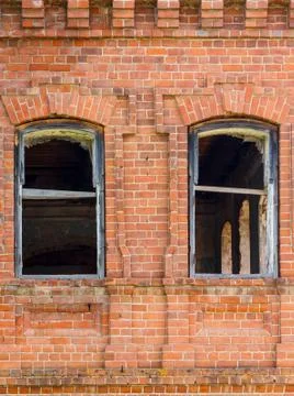 Two windows of an old destroyed building made of red brick, through which you Stock Photos