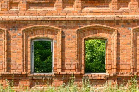 Two windows of the old destroyed building of red brick through which you can Stock Photos