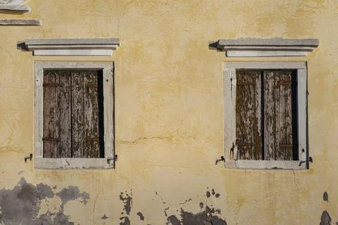 Two windows in old wall with closed brown shutters, Pellestrina island, Venetian Stock Photos