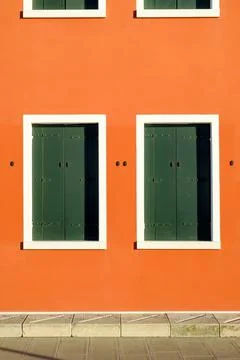 Two windows in orange wall with closed green shutters, Pellestrina island Stock Photos