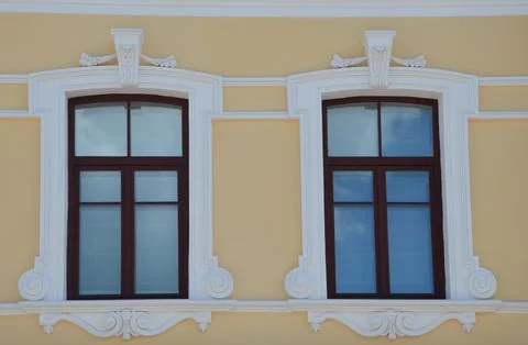 Two windows on the yellow facade of a restored building. Closed windows in a Foto stock