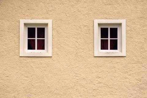 Two windows on a yellow facade  wall of an old fashioned Europe house Stock Photos