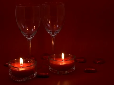Two wine glasses and two heart shaped lit red candles for St Valentine's day Stock Footage 263283456