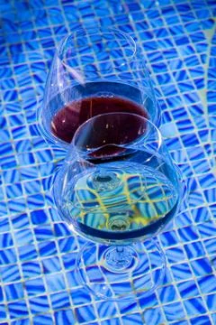 Two wine glasses floating in pool. Stock Photos