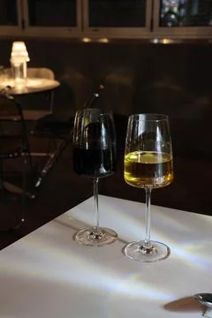 Two wine glasses, one red and one white, sit on a table Stock Photos