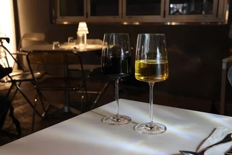 Two wine glasses, one red and one white, sit on a table Stock Photos