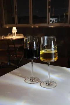 Two wine glasses, one red and one white, sit on a table Stock Photos