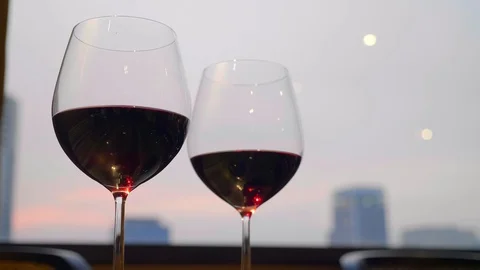 Two Wineglasses of Red Wine Stand on Table with Evening City on Background Video stock 127214084