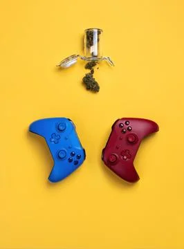 Two wireless gamepads, red and blue, lie on a yellow background, next to an o Stock Photos