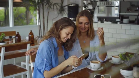 Two woman sharing coffee using smartphone in cafe in slow motion Vídeo Stock 101276384