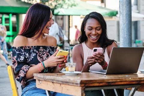 Two woman using mobiles while sitting in a cafeteria Stock Photos