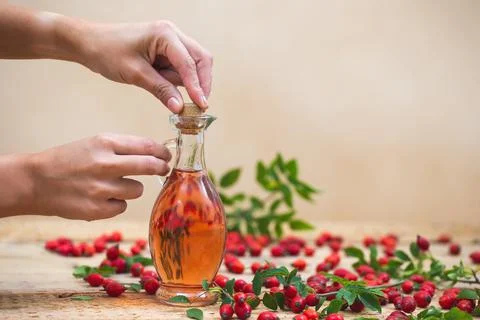 Two woman's hands closing flask with essential rosehip oil Stock Photos