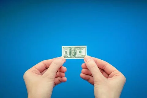Two woman's hands holding small banknote of 100 US dollar Stock Photos