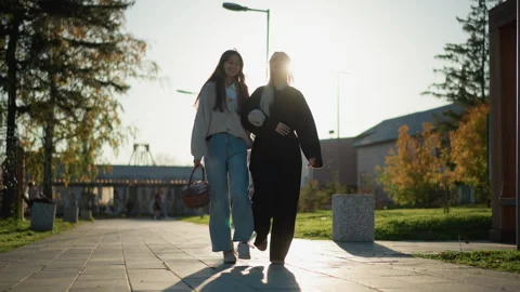 Two women and man casually walking together on autumnal public pathway under Stock Footage 346725438