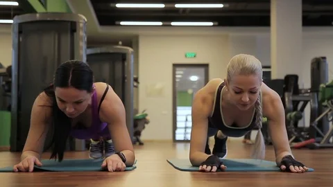 Two women are doing plank exercise in a sports club indoors. Video stock 84577591