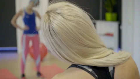 Two women are doing warm up exercises in modern gym, standing opposite to each Stock Footage 85597121