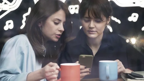 Two women are talking in a cafe and surfing the internet Stock Footage