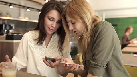 Two Women Are Talking, Looking at the Phones in a Cafe 스톡 동영상 74180655