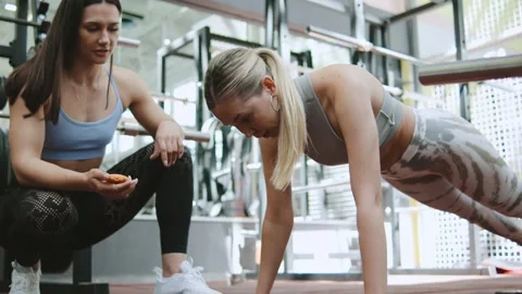 Two women are working out together in the gym: one is supporting the other durin Stock Footage 344888060