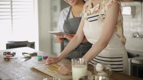 Two women  baking while checking recipe on tablet Stock Footage 159748945