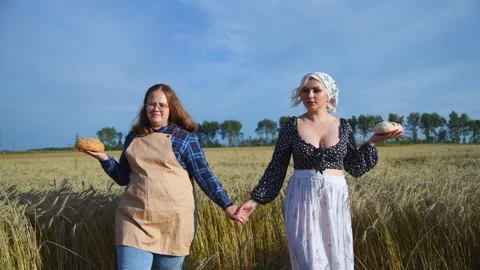 Two women with bread on wheat field Stock Footage 254979494