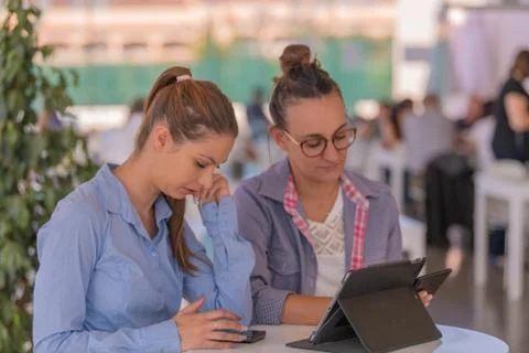 Two women busy while checking phones Stock Photos