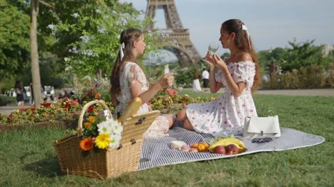 Two Women Chat While Holding Grapes And A Glass In A Park Stock Footage 341550184