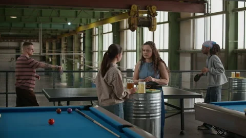 Two Women Chatting while Men Playing Ping Pong in Loft Stock Footage 332777923