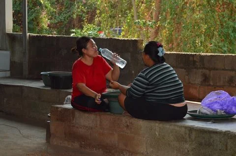 Two women chatting while one drinks bottled water Stock Photos