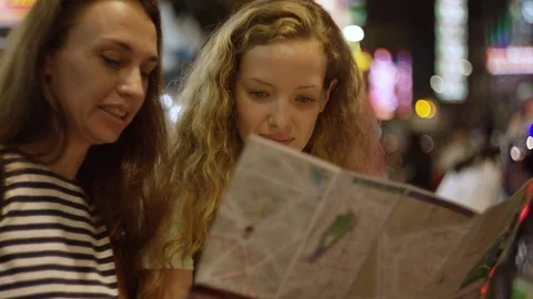 Two women checking the map on the street at night Stock Footage 73242463