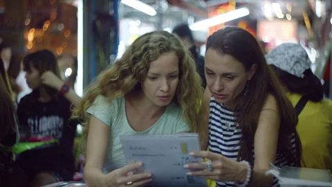 Two women checking a menu of restaurant at night Stock Footage 75292342