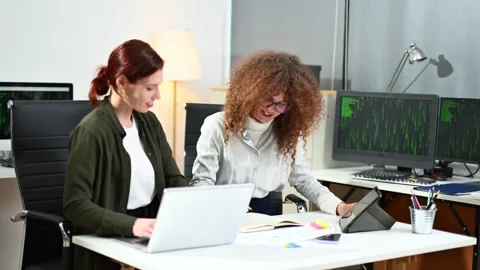 Two women coding together in a high-tech office, showcasing teamwork, softw.. Video stock 312387359