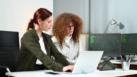 Two women coding together in a high-tech office, showcasing teamwork, softw.. Stock Footage 312387400