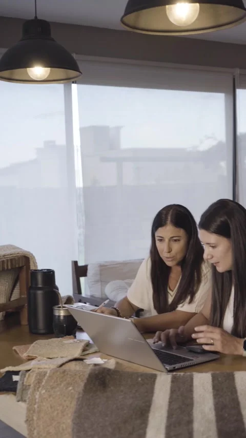 Two women collaborating closely over rustic carpet swatches Stock Footage 345758146