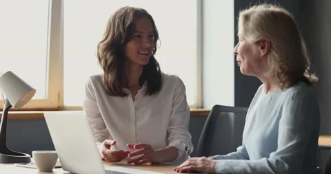 Two women colleagues talking sit at desk with laptop Stock Footage 221670011