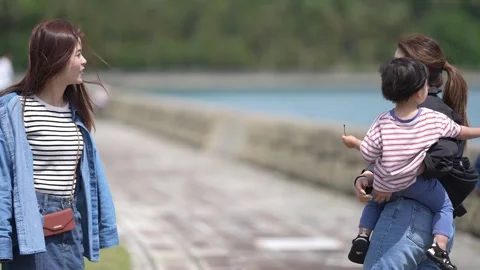 Two women converse by a lakeside path Stock Footage 340012005