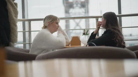 Two women conversing at cafe table with expressive hand gestures, attentive Vídeos de archivo 347541009