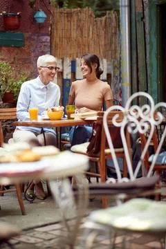 Two women, different generations, having breakfast together in outdoor cafe Stock Photos
