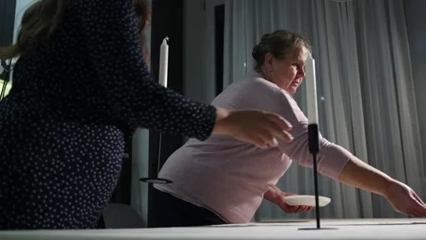 Two women of different generations setting a dining table together Видео 340061978
