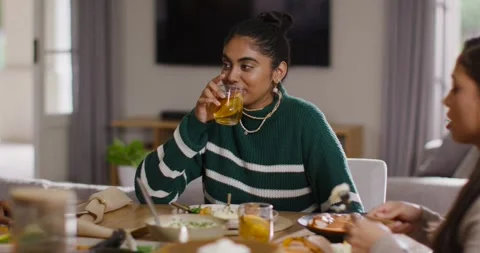 Two women dining, talking, Indian woman in green top sipping drink near cake, Stock Footage 339268311