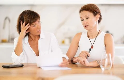 Two women discuss documents, try to solve financial problems Stockfoto's