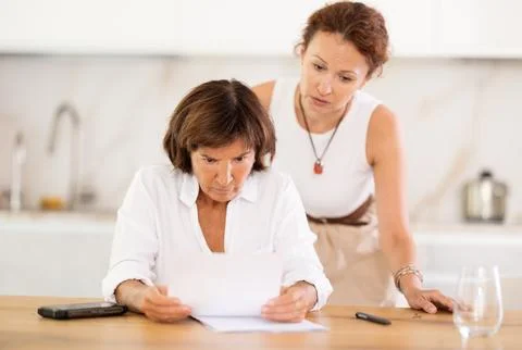 Two women discuss documents, try to solve financial problems Stock Photos
