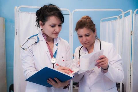 Two women doctors look at patient tests,looking through some patients medical Stock Photos