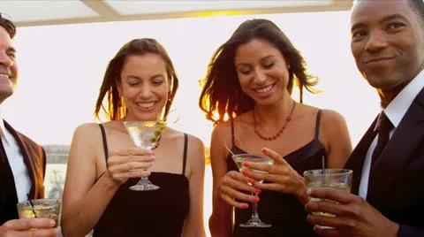 Two women drinking cocktails with men at luxury sunset party dressed in black   Stock Footage